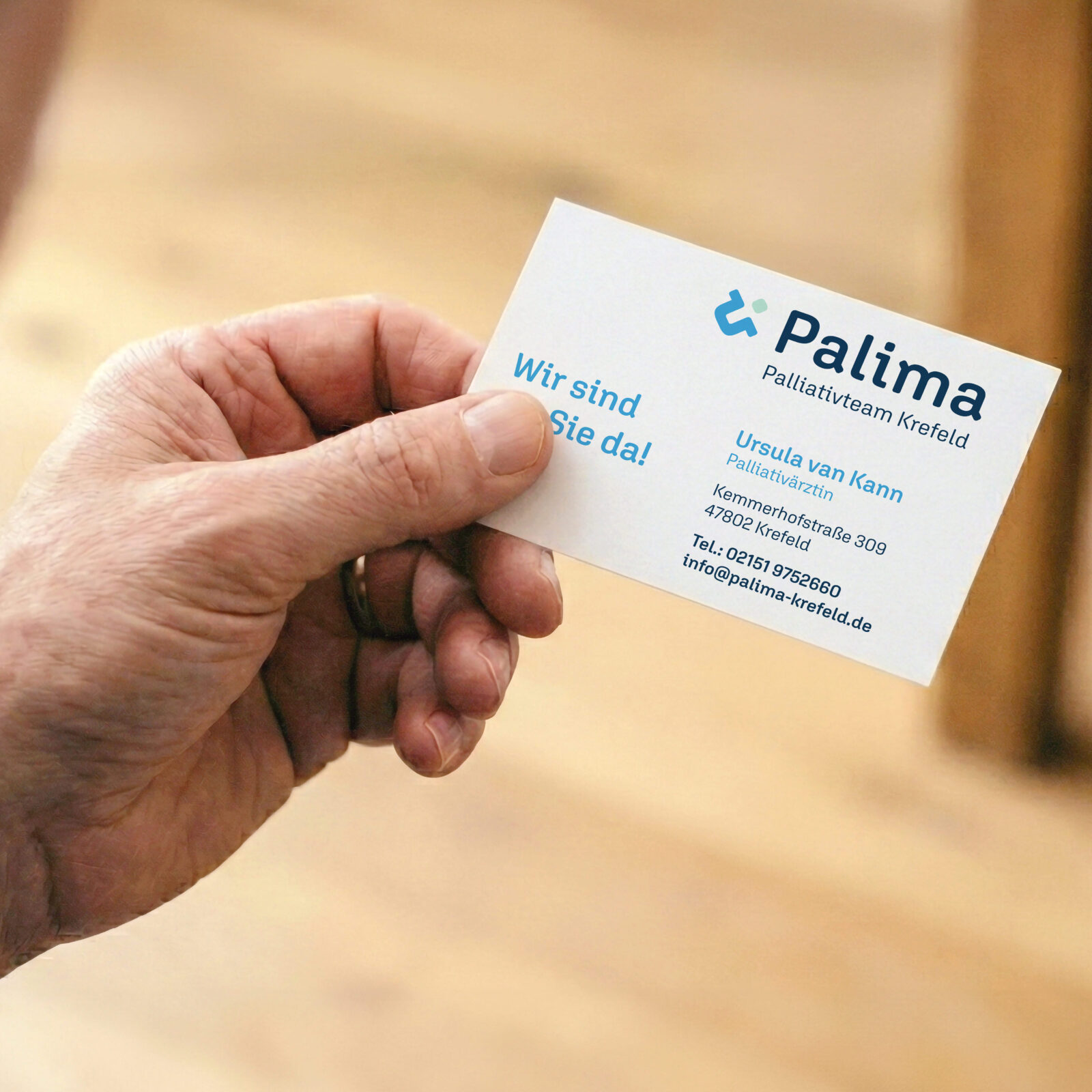 älterer Mann hält Visitenkarte von Palima Palliativteam Krefeld in der Hand, gestaltet von der Agentur montagmorgens aus Krefeld